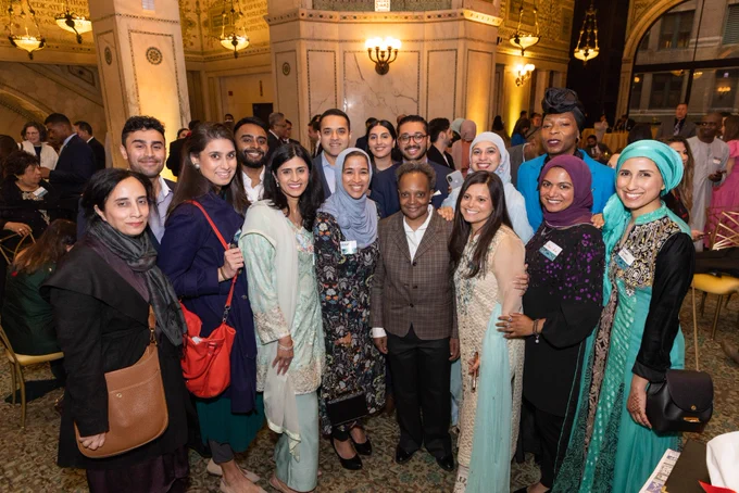 Photo ID: Mayor Lightfoot poses for a photo with a group of people. 