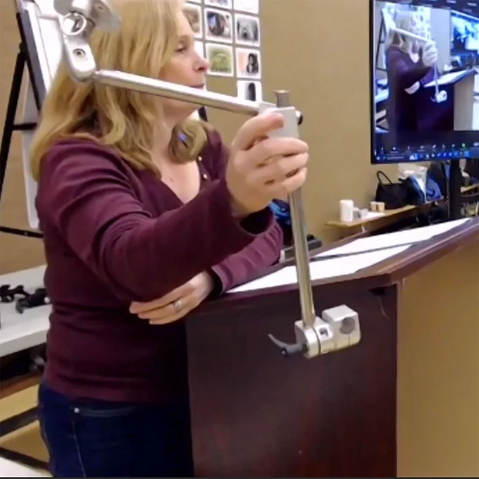 Dawn holds up a wheelchair mount component at podium.