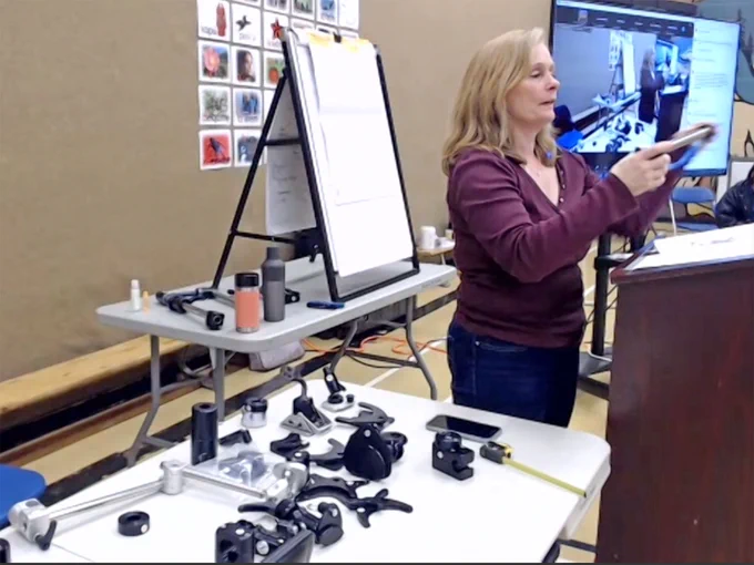 Dawn stands presenting beside a table of wheelchair mount components.