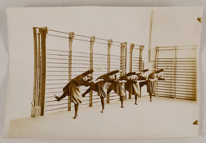 Photograph in black and white displaying women exercising using wall bars