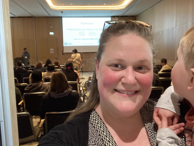 I’m in foreground smiling holding my son who’s facing Danny in the background who just gave his talk to a full room