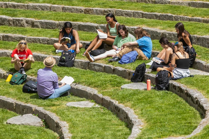 Photo of several students sitting outside at an amphitheater 