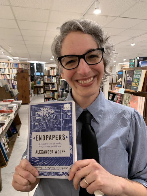 Me holding a copy of ENDPAPERS by Alexander Wolff and smiling