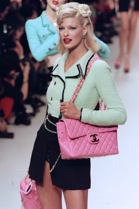 Linda Evangelista on the Chanel runway in 1995 wearing a tweed skirt suit and a bubblegum-pink encrusted Chanel bag