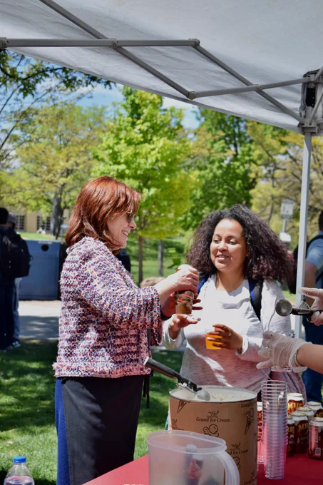 UNM President Garnett Stokes, at left in colorful vest, scoops ice cream into a float for a Lobo student.