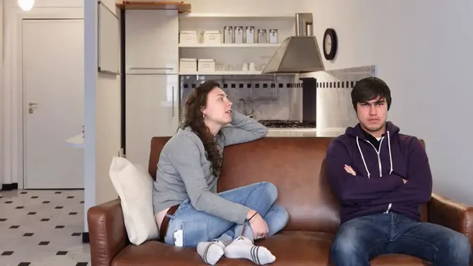 Couple sitting on a couch in an apartment.