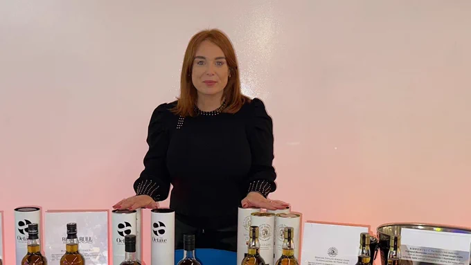 A photograph of Jen Lubbers stood at the Duncan Taylor Whisky Limited showcase table
