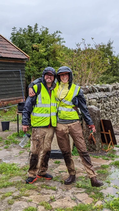 Jon, a white man, and Ophelia, a white woman, stand with their arms around each other in high-vis jackets. They look adorable and chuffed.