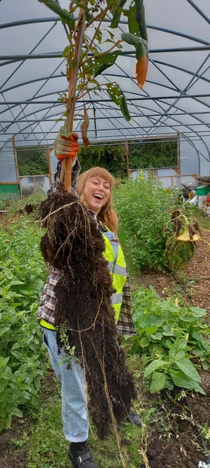 Katie, a white woman, is holding an absolute beast of a root and looking very pleased with herself.