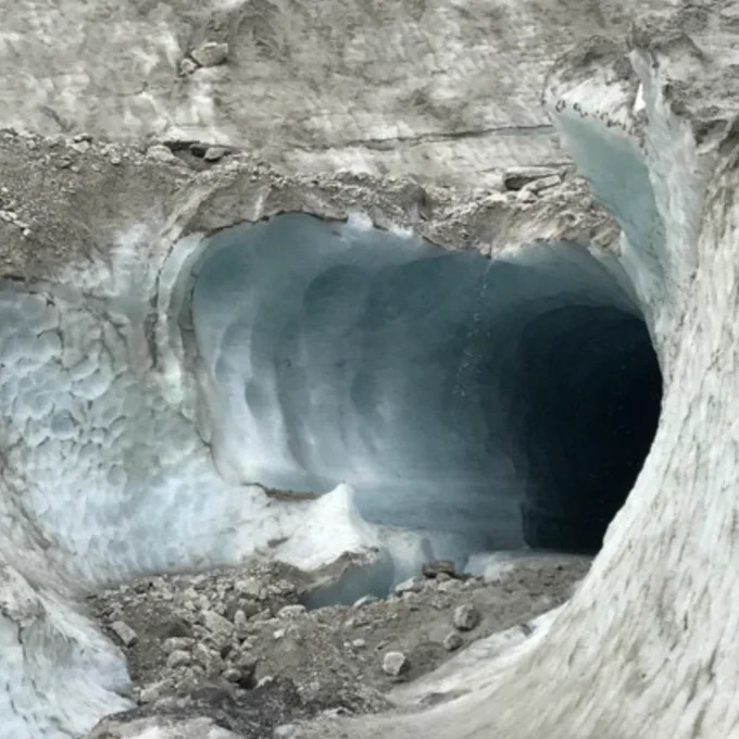 Image of an opening to a cave or tunnel through a glacier/ice/snow
