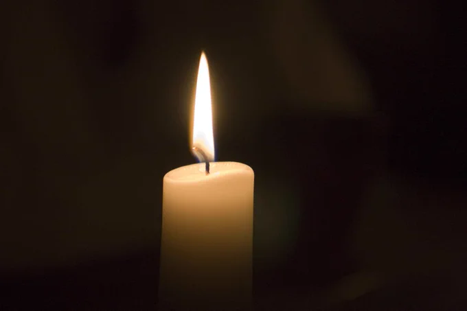 A lit candle against a dark background