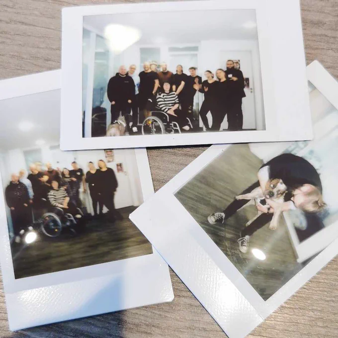 Image of three Polaroid photos. Two of them are group pictures where the Baqend employees who were present have lined up together. In the foreground is a woman in a wheelchair and to the left is a dog. In the one group picture, Mila is also present. The third photo shows a colleague cuddling with the dog. 