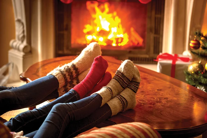 Family of three, festive socks resting by roaring fire.