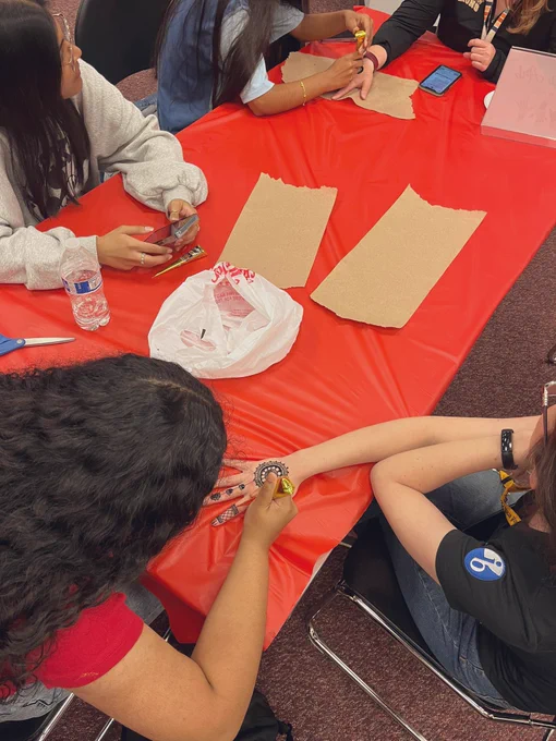 Student volunteers doing henna art on teacher hands