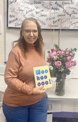 April Bragg, high school business teacher and Ohio Teacher of the Year nominee, holds a card and a flower arrangement.