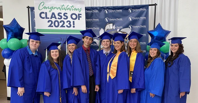 nine people in blue graduation caps and gowns. There are four mothers and their respective children in the photo who all graduated from EFSC on the same day.