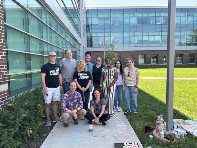 Members of CVIRL stand outside the biomedical engineering building. They are grouped all together and smiling.