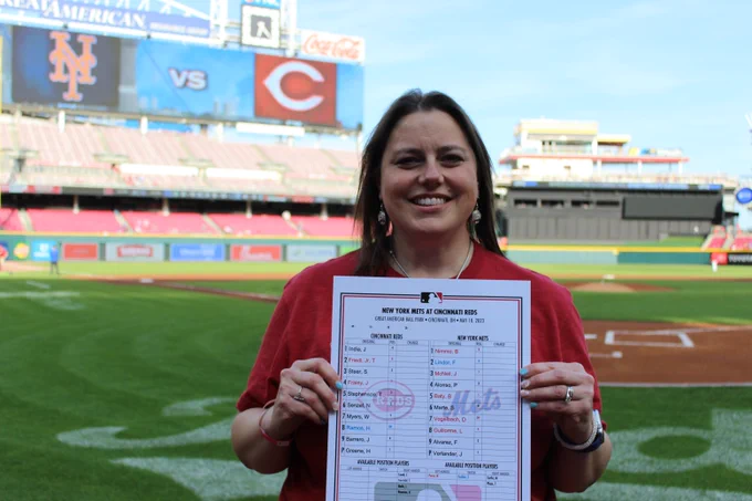 Stephanie Herber poses behind home plate with the official line-up of the 5/10/23 match-up between the Cincinnati Reds and the New York Mets. Stephanie served as Honorary Captain prior to the game.