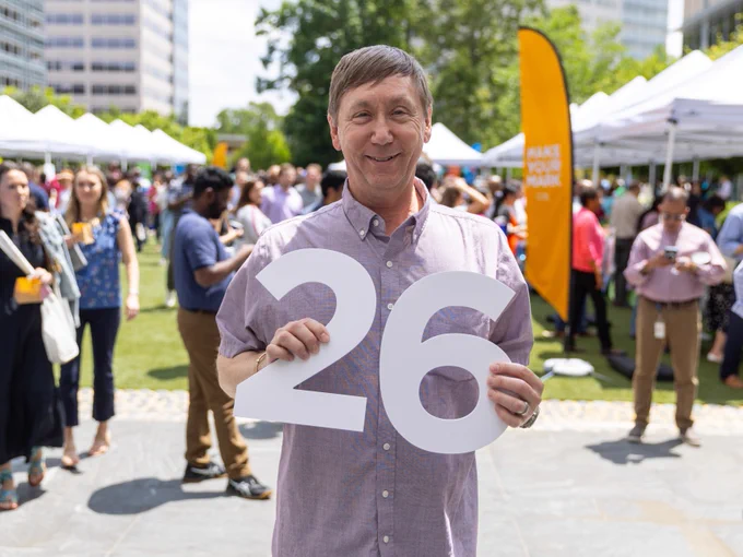 A man holding the number "26"