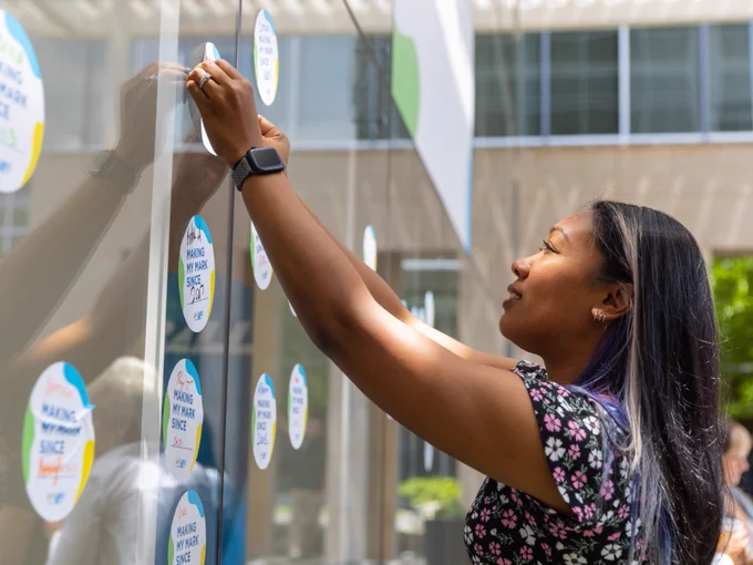 A woman placing a sticker on a wall
