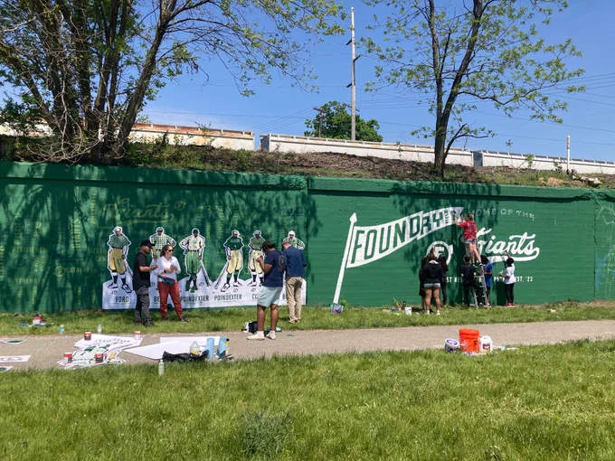 Students painting on mural wall