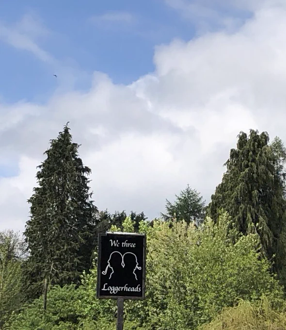 We Three Loggerheads sign in front of green trees and blue sky