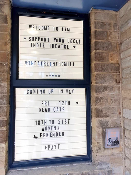 The retro 'cinema marquee' outside the theatre which reads: "Welcome to TiM | 🖤 Support your local indie theatre 🖤 | @theatreinthemill | Coming up in May | Fri 12th DEAD CATS | 18th to 21st Women's Weekender"