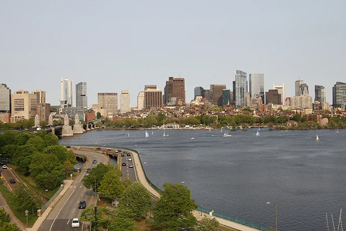 Boston skyline as seen from a rooftop at MIT with sailboats on the Charles River.