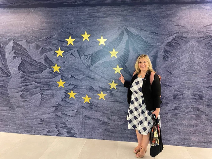 Merili Soosalu from Cyber4Dev in Costa Rica for Cyber Awareness Week. She is pointing towards a mural depicting the EU emblem. 