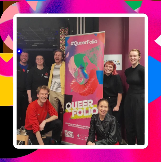 Seven people gather around a colourful Queer Folio poster. They smile to the camera.