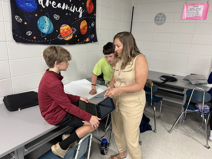 Innovative Teacher Meagan Ralph consults with a pair of students on a class assignment.