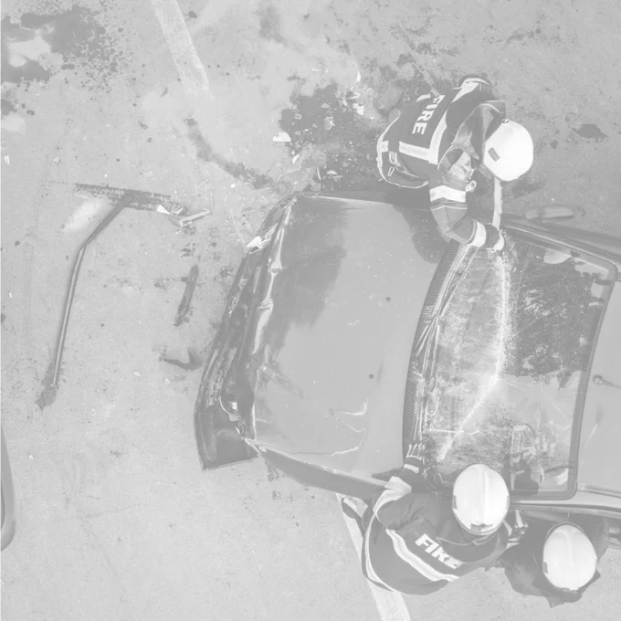 Photo of two firefighters tending to a car that has been in an accident