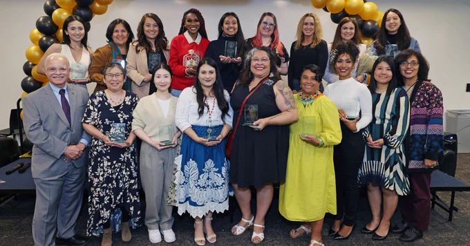 A group of 17 award recipients and the university president smiling.