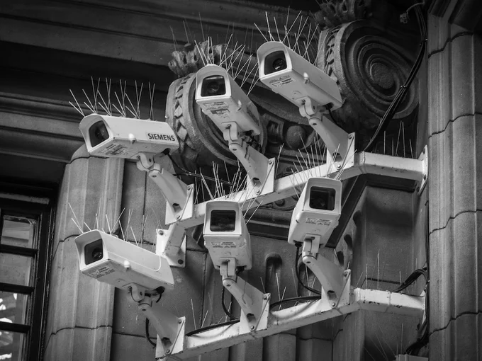 6 CCTV cameras with bird spikes mounted on a classical style building with corinthian detail