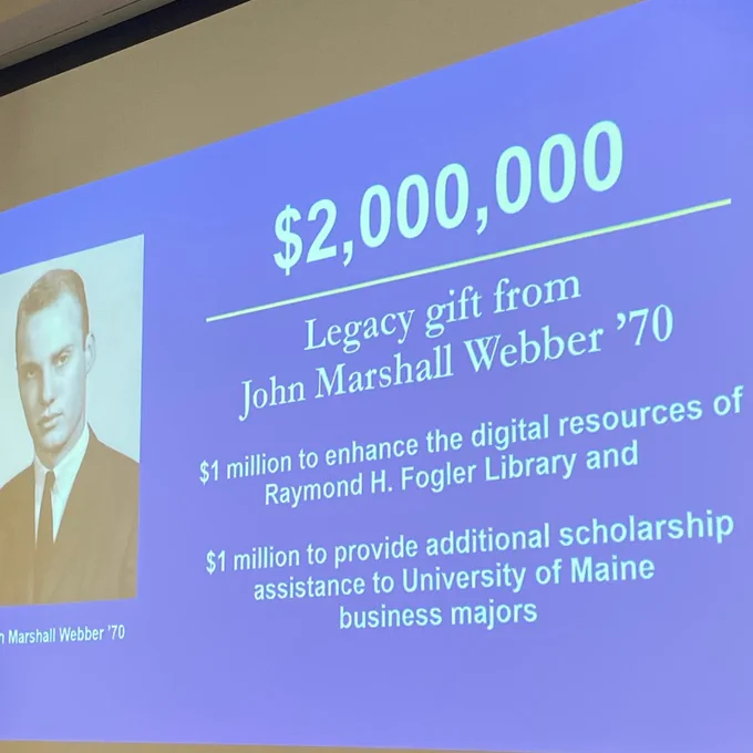 A photo of a powerpoint slide displaying a photo of John Marshall Webber and text that reads "$2,000,000; Legacy gift from John Marshall Webber; $1 million to enhance the digital resources of Raymond H. Fogler Library and; $1 million to provide additional scholarship assistance to University of Maine business majors." 