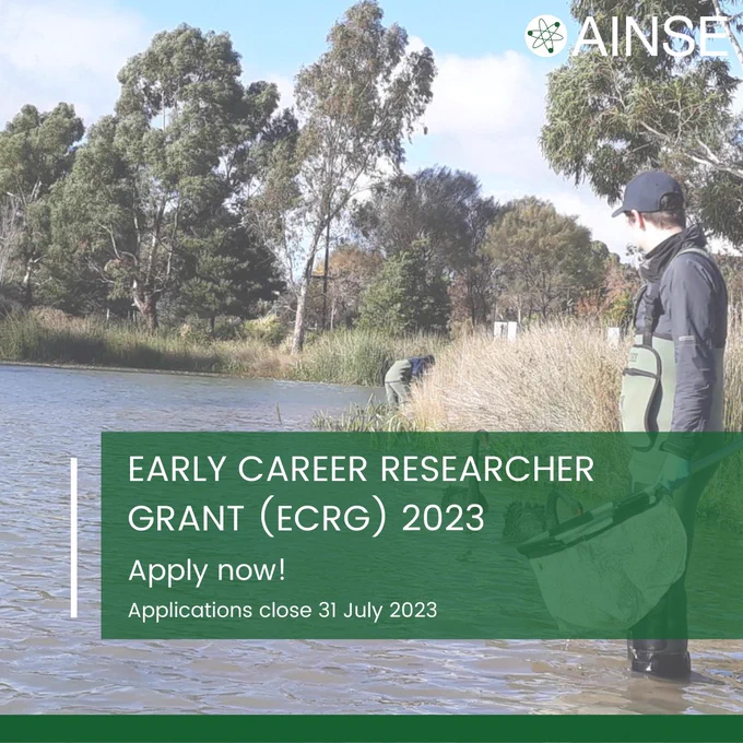 Photograph of an AINSE-supported researcher holding a large sampling net and standing in shallow waters in a Victorian wetland, looking away from the camera at a nearby black swan. Tall grass and large trees are visible in the background. Overlaid on a green rectangle is the text: "Early Career Researcher Grant (ECRG) 2023: Apply now! Applications close 31 July 2023". Photo credit: Kathryn Hassell