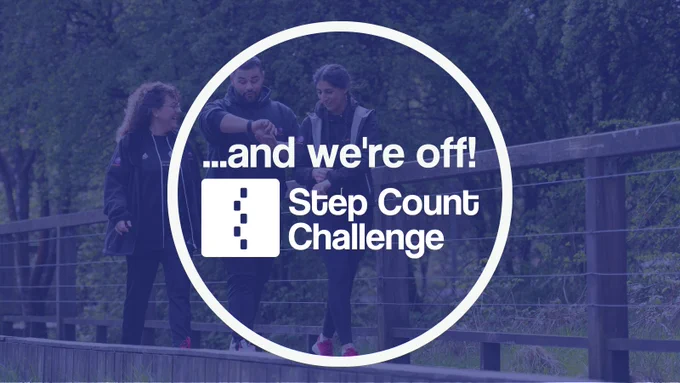A promotional graphic with an image of three people in dark clothing walking along a woodland boardwalk with a white Step Count Challenge logo within a white circle and blue transparent filter over the top.