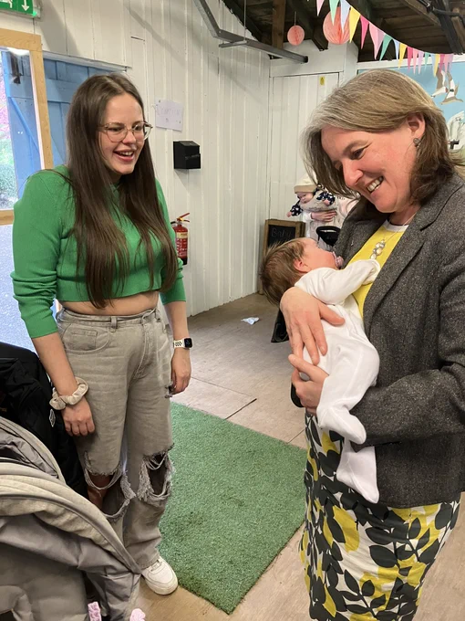 Minister holding a baby with a new mum