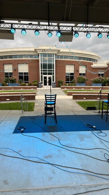 Outdoor amphitheater stage set up with blue carpets and blue stage lights