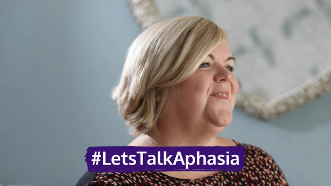 Kelly has short blonde hair and is looking away from the camera. The photo is of her head and shoulders. Text on the image says #LetsTalkAphasia.