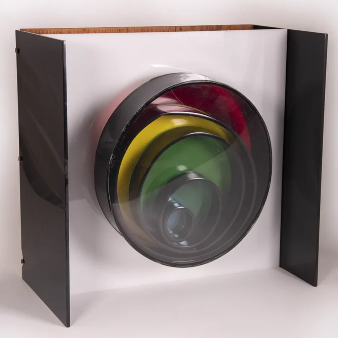 Concentric circles made of colored glass, nested within each other. This sculpture by poet Mary Ellen Solt lights up and spins when plugged in.