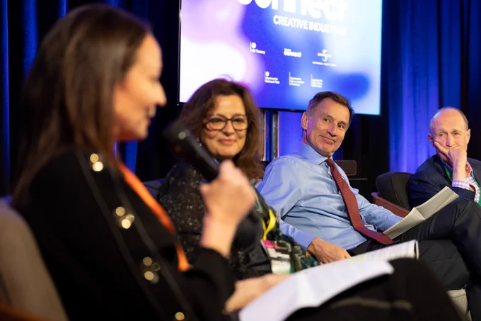 Chancellor Jeremy Hunt sits on stage alongside industry leaders from the creative sector.  A screen saying "Treasury Connect - Creative Industries" can be seen in the background.