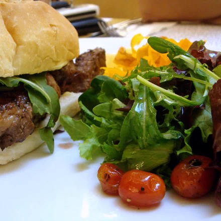 Photo of a hamburger with arugula and tomatoes