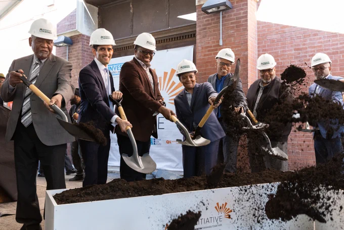 Photo ID: Mayor Lightfoot stands with a group of people with hardhats and shovels, digging. 