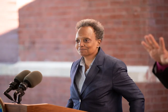 Photo ID: Mayor Lightfoot is standing behind a microphone. 
