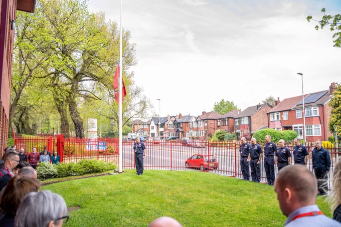 staff outside headquarters observing the silence with the flag at half mast