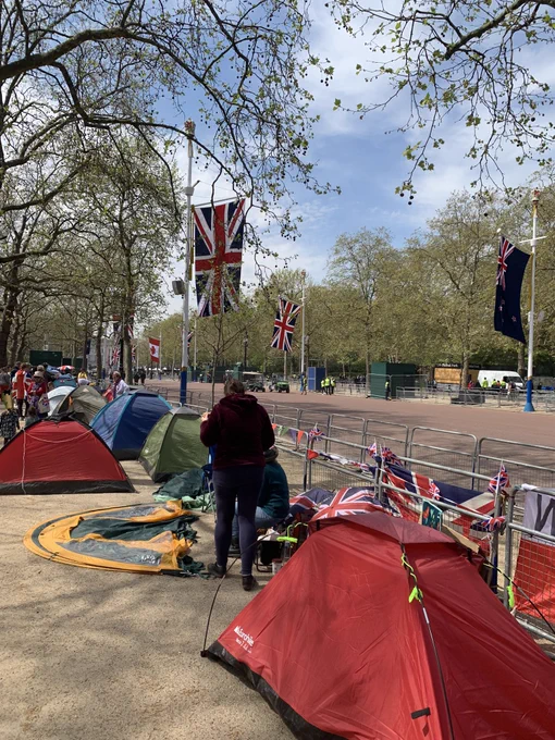 The mall leading to Buckingham palace. There are lots of tents as people are camping out ahead of the coronation. There are large union jacks hanging up along the mall.