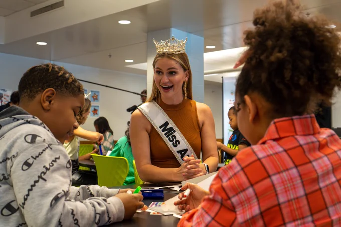 Miss America sits with students.