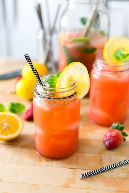 jars filled with lemonade garnished with black and white straws and lemon slices