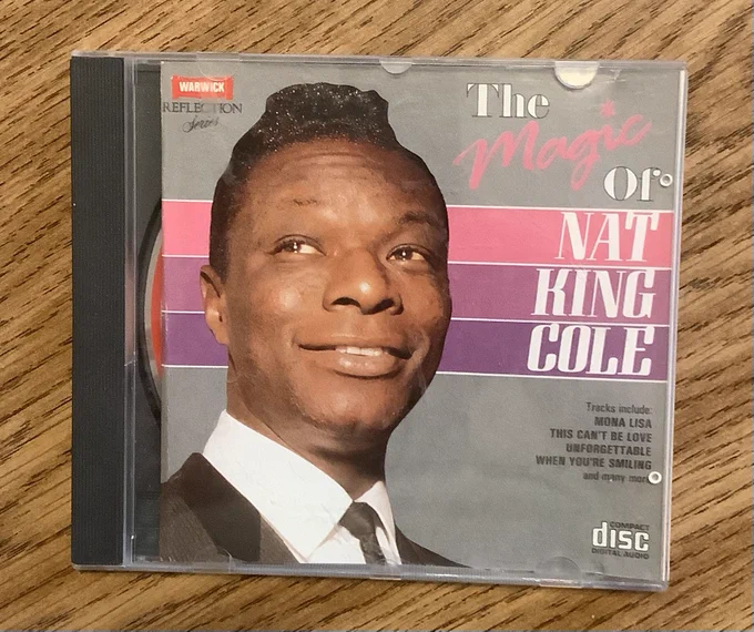 Photo of a cd cover with a picture of Nat king Cole - the cd is the magic of Nat king Cole and features listed tracks such as Mona Lisa, This can’t be love and unforgettable